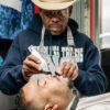 Barber performing grooming on customer.