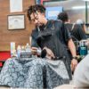 Barber performing grooming touches on customer.